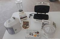 Osterizer blender, Braun juicer (larger), rotary grater box, Toastmasters Snackster sandwich maker with manual, Braun citrus juicer
