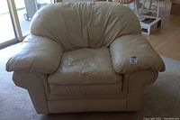 Front view of cream leather armchair showing plush armrests and cushioned backrest.