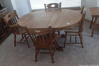 Full view of the oak oval dining table with four matching chairs surrounding it, showing table top and chairs arrangement.