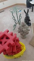 Photo showing red waffle blocks in yellow bag, rabbit statue, cornucopia statue, and iron plant stand with decorative scrollwork