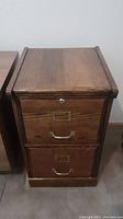 Wooden 2 drawer locking file cabinet, front view showing wood grain finish and metal handles with label slots