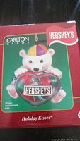 Front of boxed Hershey's Holiday Kisses ornament with polar bear artwork and heart-shaped ornament with Hershey's Kisses inside.