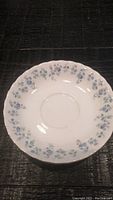 Top view of Memory Lane pattern Royal Albert bone china saucer with blue floral design and scalloped edges with gold trim