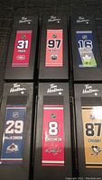 Photo showing six Tim Hortons branded NHL hockey sticks with player name, number, and team logo on each.