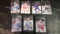 Seven sealed miniature hockey card packs arranged in two rows showing various NHL players in action poses wearing 1990s team uniforms.