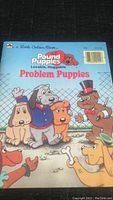 Front cover of the vintage 1986 Pound Puppies Little Golden Book titled Problem Puppies showing illustrated puppies in colorful outfits and a chain-link fence background.