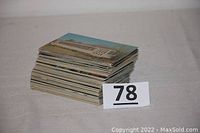 Stacked pile of vintage USA postcards showing top card with building and lawn scene.