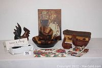 Full lot view showing four Kona bowls stacked in a large serving bowl, wooden utensils, placemats and napkins folded, decorative chickens, basket, and wall art.