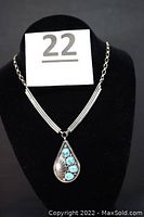 Full view of the silver necklace with teardrop pendant featuring four turquoise stones and chain with no clasp, displayed on black bust.