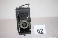 Full view of Kodak Vigilant Junior Six-20 folding camera standing upright showing bellows and metal body with worn black finish.