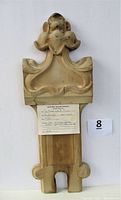 Front view of the carved wooden decorative panel showing ornate detailing and slight damage near top edges.