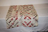 Full view of the folded patchwork baby quilt showing the varied colors and stitching.