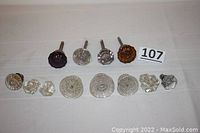 Photo showing four antique glass and brass door knobs, one amethyst, one amber, and two clear glass, along with eight clear glass drawer pulls.