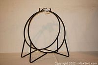 Full view of heavy duty circular wrought iron log rack showing circular frame and triangular base supports.