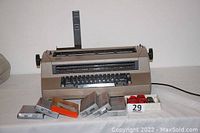 Front view of IBM Correcting Selectric III typewriter with various boxed ribbons and correction tapes arranged in front.