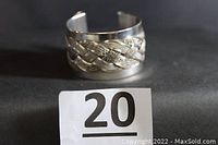 Front view of the silver-tone wide cuff bracelet showing detailed braided design.