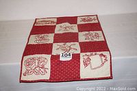 Front view of the thin decorative quilt laid flat showing the checkered red and white pattern with embroidered squares.