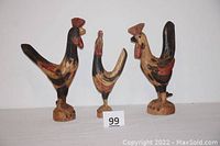 Photo showing all three hand-carved wooden rooster figurines side by side with size reference card.