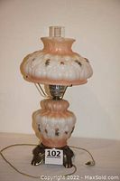 Lamp powered off showing flower decals on opaque glass body and shade with metal base.
