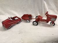 Hallmark Galleries 1955 classic red pedal car, tractor, and trailer on white fabric background