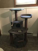 Front angle photo of the cat scratching post tower showing platforms, cubed hideaway, rope toy, and base structure