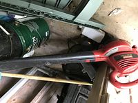 Red Craftsman electric blower lying on floor with black nozzle tube, surrounded by other workshop items.