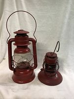 Two red vintage lanterns side by side on a white background, showing the overall size and condition.