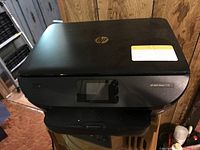 Black HP Envy Photo 7155 all-in-one printer closed, front view showing logo and touchscreen panel