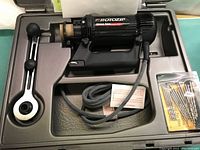 Rotozip Spiral Saw with attached cord and brass chuck, fitted in molded plastic carrying case with accessory handle and drill bits.