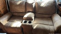 Full front view of brown microfiber reclining loveseat with center console and cup holders