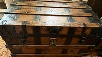 Full top and front view of vintage solid wood steamer trunk showing wooden slats, metal bands, lock plate, and latch.