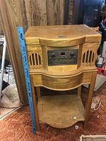Front view of Philco stereo console showing wood finish cabinet, speakers, control panel, and ruler for scale.