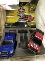 Two RC trucks in foam packaging insert with Xmods Evolution promotional cards visible