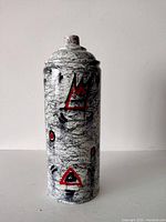 Front view of the painted spray can showing cracked white base and red abstract shapes