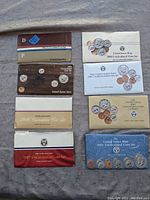Eight United States Mint uncirculated coin sets from 1984 through 1991 displayed on ground surface.