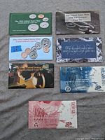 Seven United States Mint uncirculated coin sets from 1993 through 1999 are displayed on a surface.