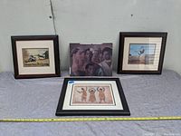 Four framed African American art pieces arranged for display, including a signed print and other paintings/prints.