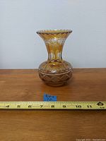 Front view of the amber cut glass vase showing shape, patterns, and measurement tape indicating approximately 7 inches height.