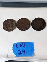Three Canadian pennies dated 1900, 1917, and 1918 shown on white background with blue tag labeled 'Lot 29'. Coins show various wear and patina.