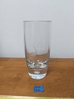 Full view of a tall clear glass vase with etched leaping deer design on the front.