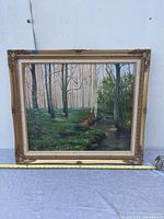 Full view of the framed oil on canvas painting showing wooded river scene with trees and water under natural light.