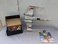 Top view of large X-Wing toy, Star Wars flap book, and measuring tape showing approximate size of 20 inches.