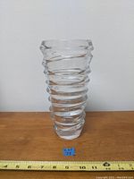 Full view of the clear heavy twister glass vase on wooden surface with measuring tape showing height approximately 11 inches.