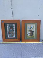 Photo of two framed bird prints side by side on a white surface with measuring tape for scale