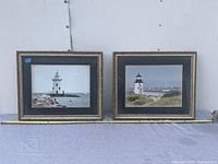 Two framed lighthouse photographs side by side on a wall for display.