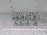 Ten vintage Libby Gibraltar attributed glasses arranged in two rows on a tabletop with a measuring tape indicating size.