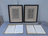 Two framed Roman-themed prints with five medallions each, along with four loose antique book pages laid out flat with measuring tape for scale.