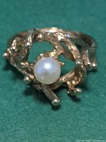 Front view showing gold tone coral reef design with central white pearl