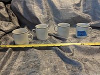 Four vintage white demitasse cups with small handles, displayed with measuring tape showing about 2.5 inches tall each.