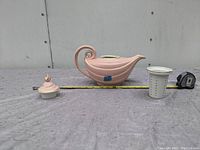 Photo showing the tea kettle, lid, and tea strainer arranged side by side with measuring tape for scale.